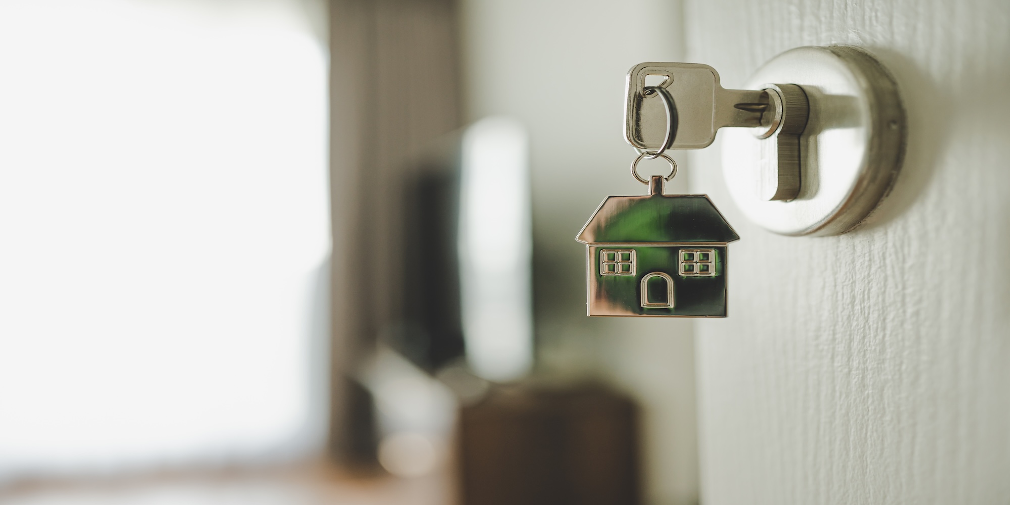 A house on a keyring with the key in a lock. 